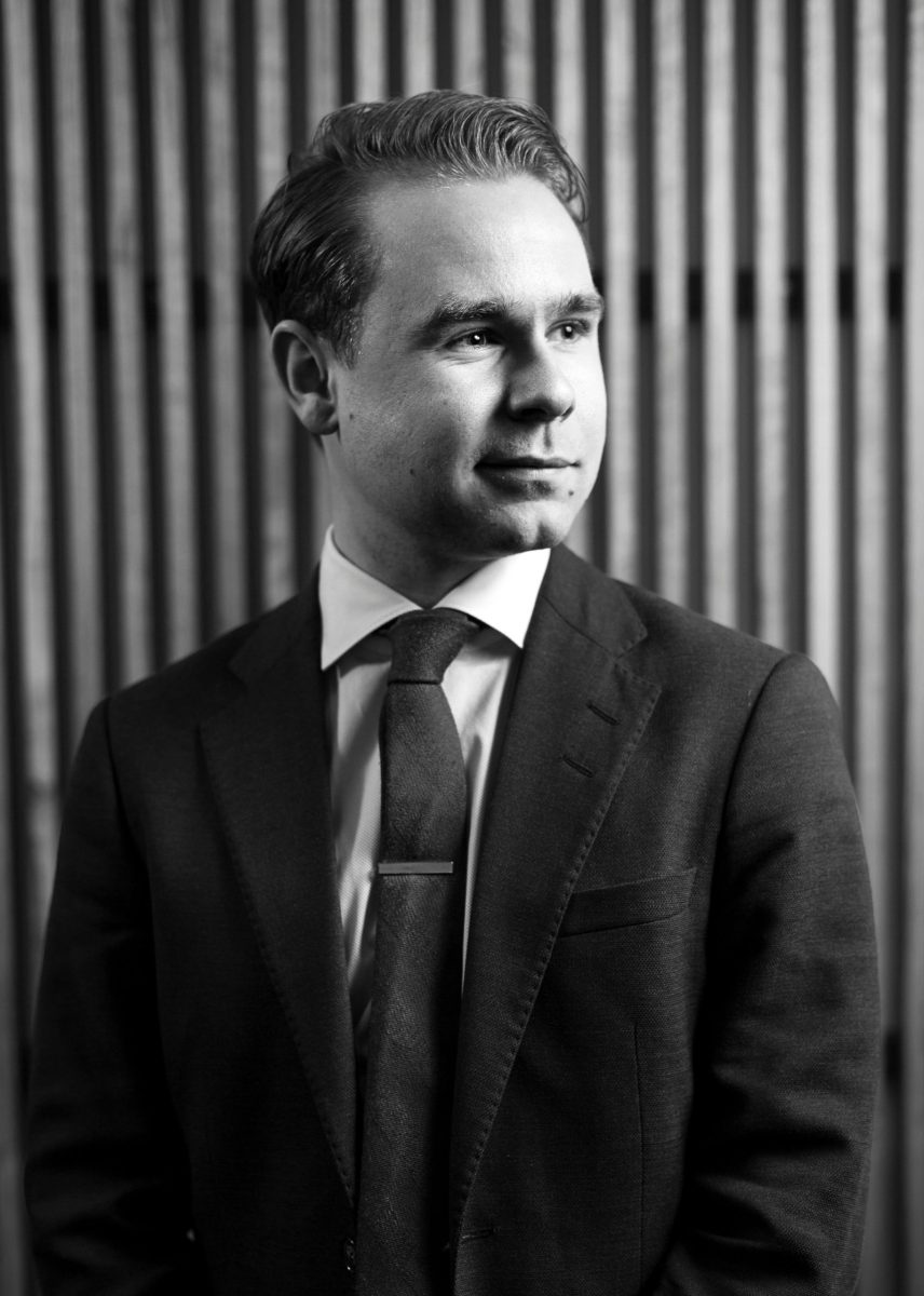 Black and white portrait of an adult businessman in a suit with a confident expression.